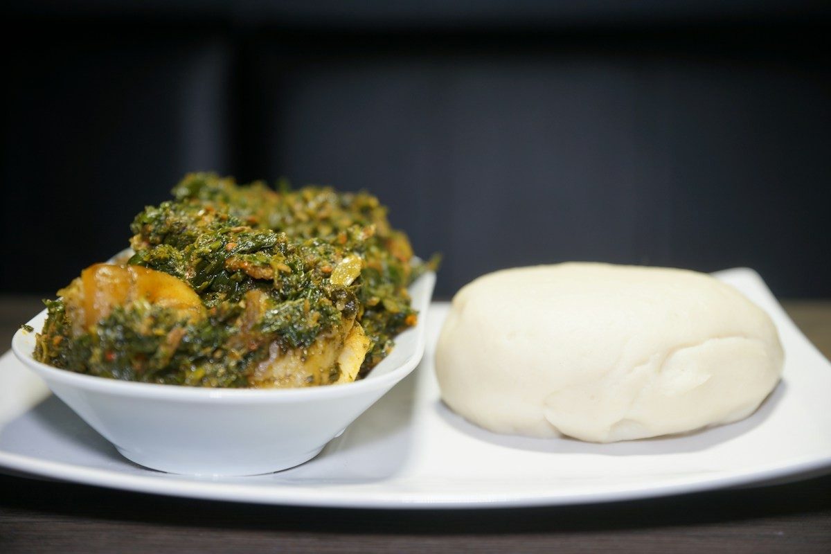 Bol de sauce aux légumes verts servi avec une boule de pâte blanche